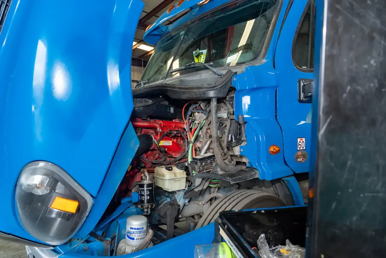 Engine bay of a blue semi truck opened up for an engine rebuild