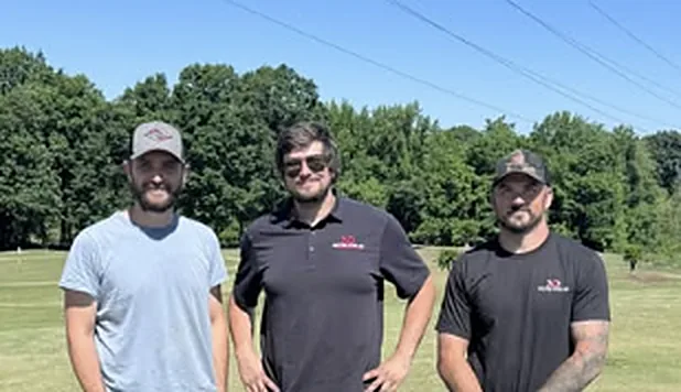 Three team members standing on a golf course
