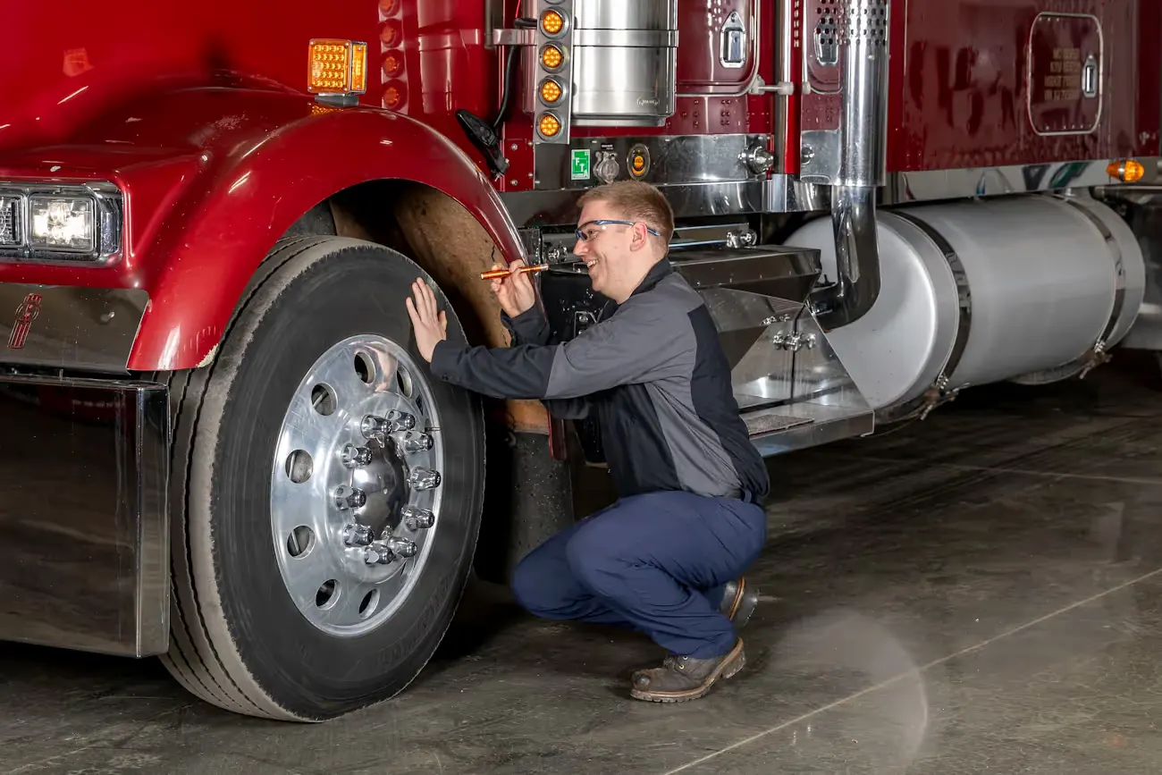 Mechanic inspecting the wheel end of a red semi truck